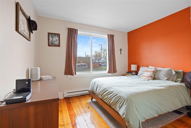 bedroom with a baseboard radiator, baseboards, and hardwood / wood-style flooring