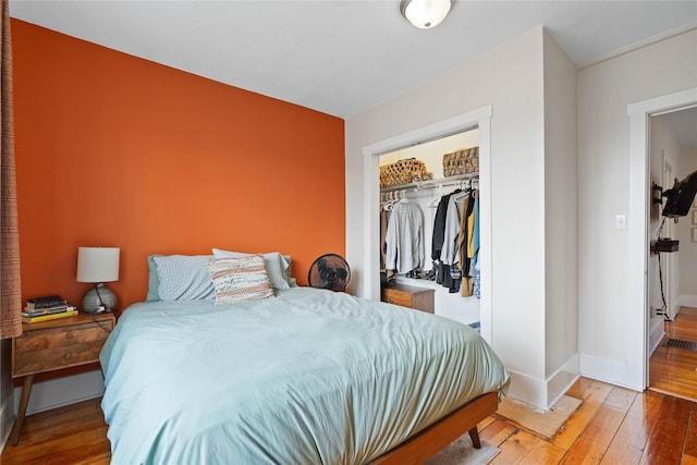 bedroom featuring a closet, a walk in closet, hardwood / wood-style flooring, and baseboards