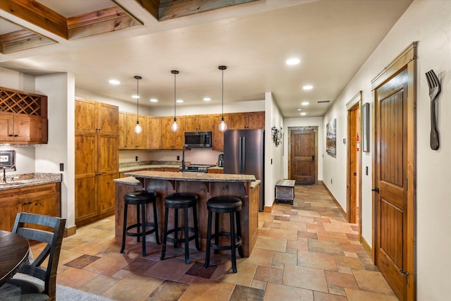 kitchen featuring recessed lighting, stone tile flooring, appliances with stainless steel finishes, and brown cabinets