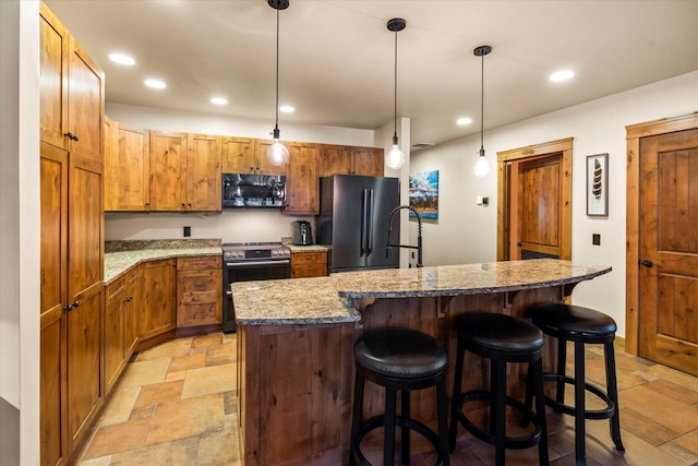 kitchen featuring a kitchen bar, stainless steel electric stove, freestanding refrigerator, and stone finish flooring