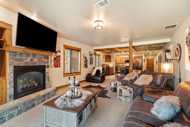 living room with visible vents, a stone fireplace, and carpet flooring