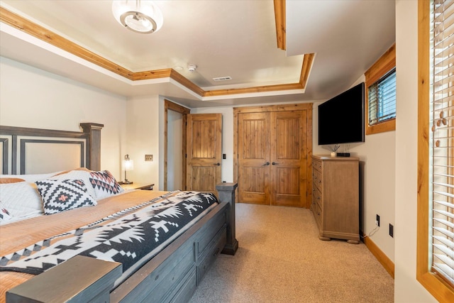 bedroom featuring baseboards, visible vents, light colored carpet, and a tray ceiling