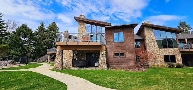 rear view of house with a chimney, a patio area, a yard, and stone siding