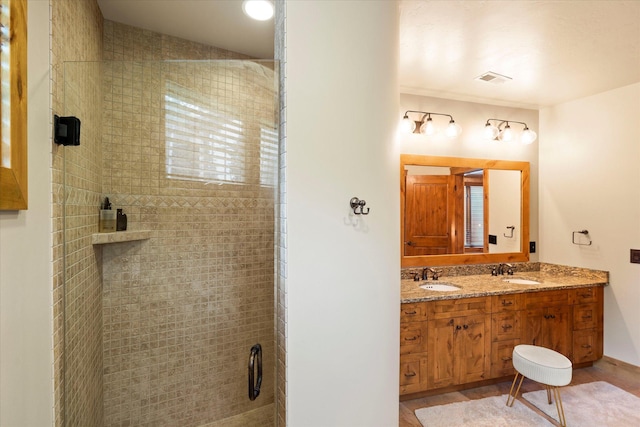 bathroom with a sink, double vanity, and tiled shower
