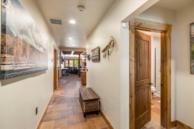 hall featuring baseboards, visible vents, stone finish floor, and recessed lighting