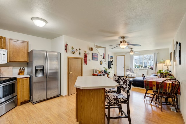 1923 Montana St Unit B, Missoula, MT 59801 - kitchen featuring light countertops, ceiling fan, appliances with stainless steel finishes, brown cabinets, and light wood finished floors