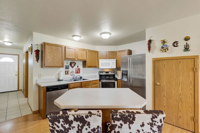 1923 Montana St Unit B, Missoula, MT 59801 - kitchen featuring a textured ceiling, a kitchen island, appliances with stainless steel finishes, light countertops, and a sink
