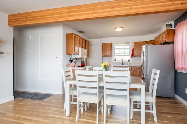 1634 W Central Ave, Missoula, MT 59801 - kitchen with white microwave, freestanding refrigerator, light countertops, light wood-style flooring, and brown cabinetry