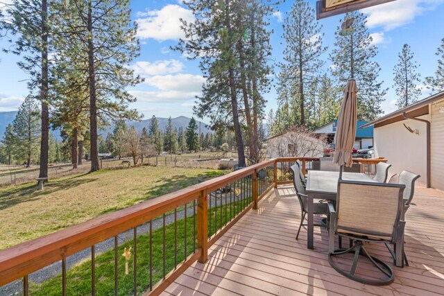 538 Bighorn Dr, Thompson Falls, MT 59873 - wooden deck with outdoor dining space, a mountain view, and a lawn