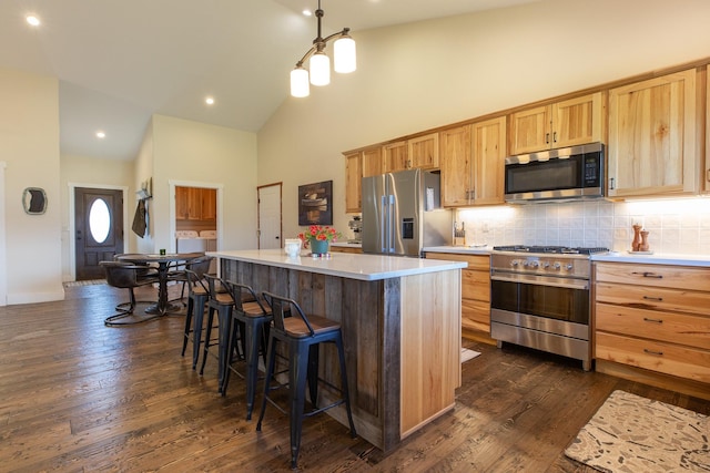 716 Shadow Dancer Way, Stevensville, MT 59870 - kitchen with stainless steel appliances, high vaulted ceiling, light brown cabinets, a breakfast bar, and decorative backsplash