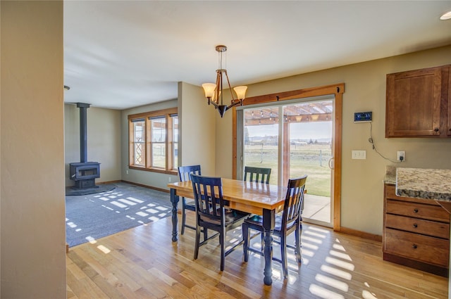 3774 Juliet Dr, Helena, MT 59602 - dining room with a wood stove, an inviting chandelier, light wood-style flooring, and baseboards