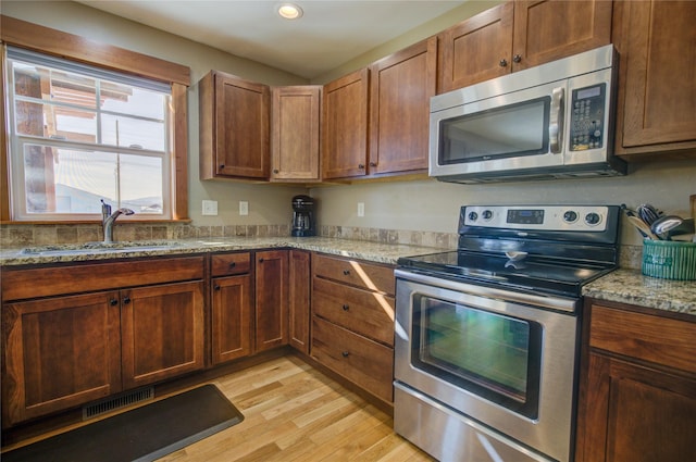 3774 Juliet Dr, Helena, MT 59602 - kitchen featuring light stone counters, appliances with stainless steel finishes, light wood finished floors, a sink, and visible vents