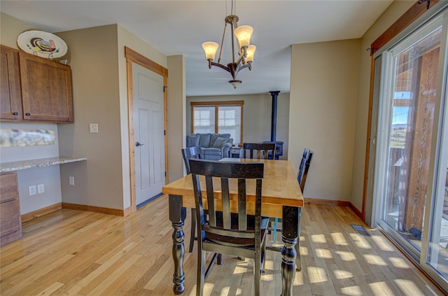 3774 Juliet Dr, Helena, MT 59602 - dining area with a wood stove, light wood finished floors, a notable chandelier, and baseboards