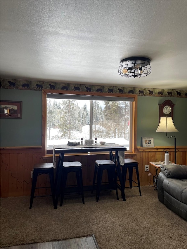 3806 Mt Highway 83 Unit 2, Seeley Lake, MT 59868 - carpeted dining space featuring a wainscoted wall, a textured ceiling, and wooden walls