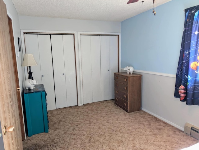 2599 Pike Dr, East Helena, MT 59635 - carpeted bedroom with baseboard heating, a textured ceiling, a ceiling fan, and multiple closets