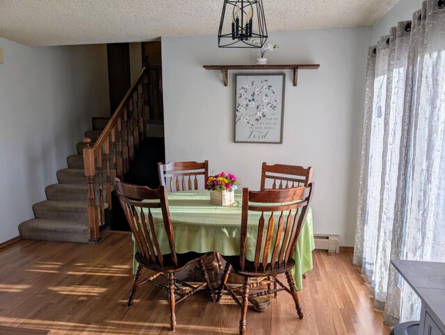 2599 Pike Dr, East Helena, MT 59635 - dining area featuring stairs, a baseboard heating unit, wood finished floors, and a textured ceiling