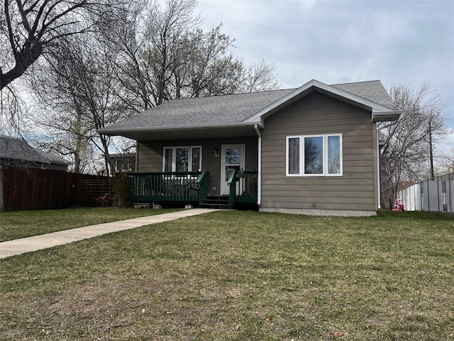 view of front of house featuring a front yard, fence, and a shingled roof