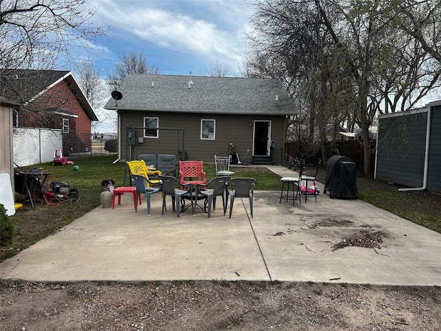 back of property with a lawn, a patio area, a fenced backyard, and a shingled roof