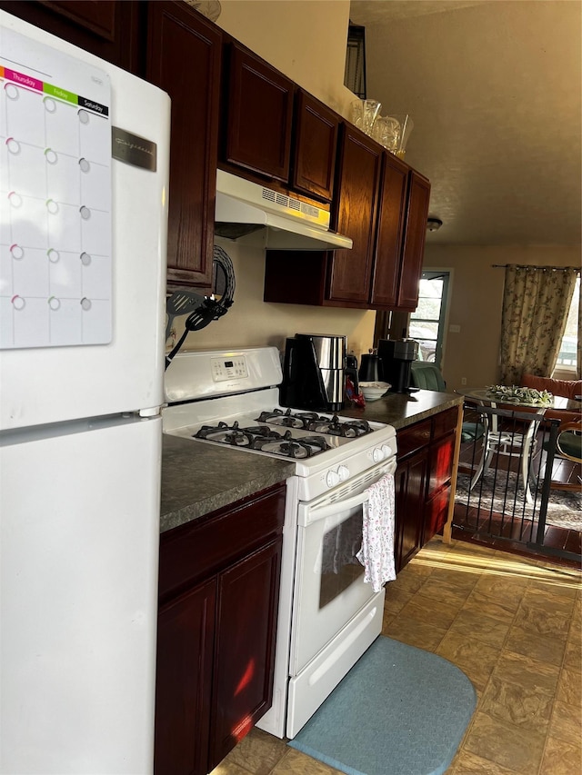 kitchen with under cabinet range hood, dark countertops, and white appliances