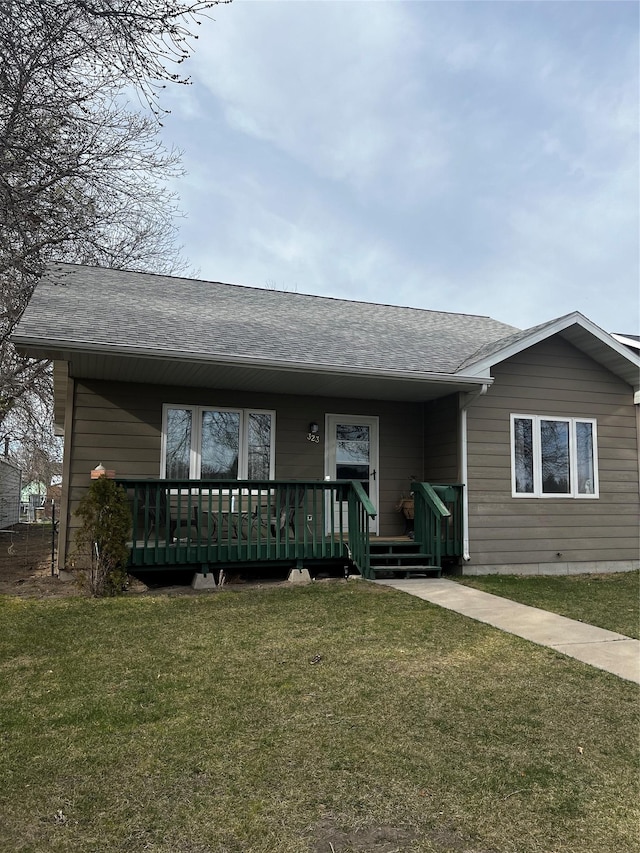 ranch-style house with a front yard, a porch, and roof with shingles