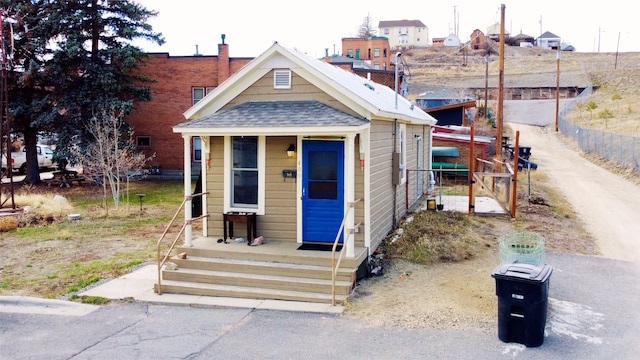 view of front of house featuring roof with shingles and fence