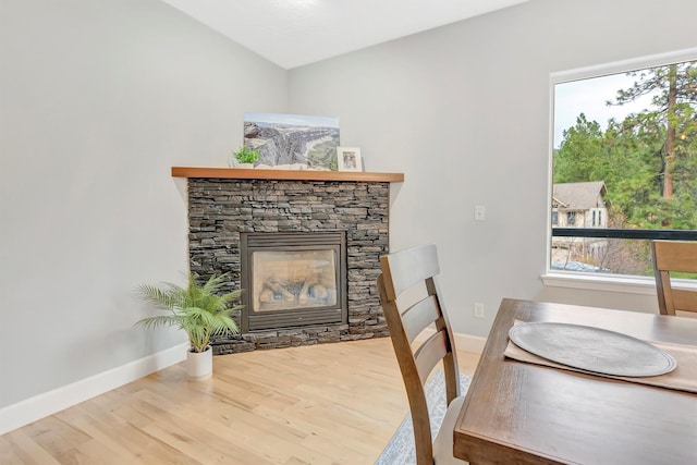 15022 Romulus Ln, Frenchtown, MT 59834 - dining area featuring wood finished floors, baseboards, vaulted ceiling, and a stone fireplace