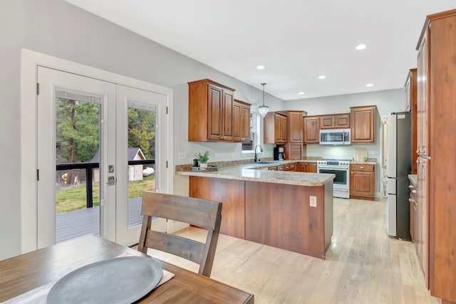 15022 Romulus Ln, Frenchtown, MT 59834 - kitchen with stainless steel appliances, a peninsula, light countertops, brown cabinetry, and light wood finished floors