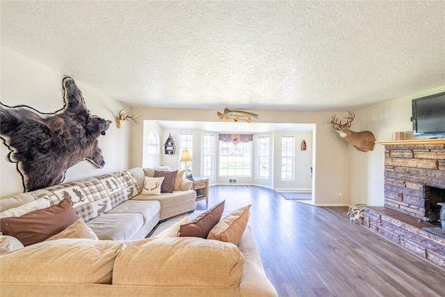 139 Highwood Dr, Libby, MT 59923 - living room with wood finished floors, a textured ceiling, baseboards, and a stone fireplace