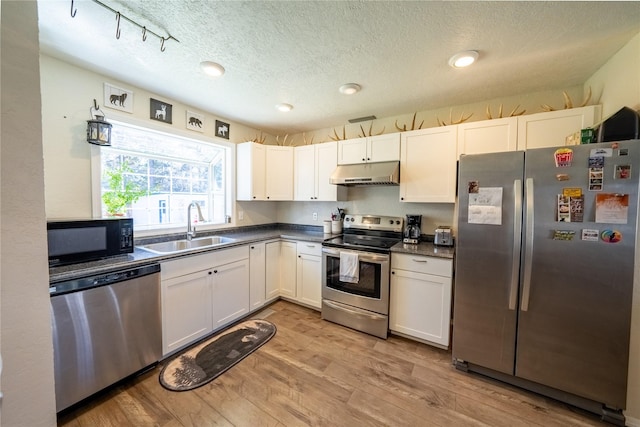 139 Highwood Dr, Libby, MT 59923 - kitchen with appliances with stainless steel finishes, under cabinet range hood, a sink, dark countertops, and a textured ceiling