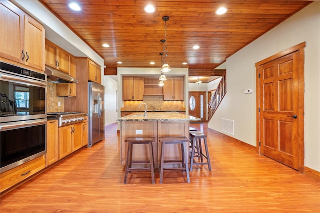 kitchen featuring wooden ceiling, appliances with stainless steel finishes, under cabinet range hood, and light wood-style flooring