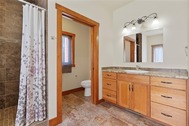 full bath featuring vanity, baseboards, toilet, and tiled shower