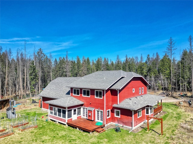 136 N Fork Trl, Columbia Falls, MT 59912 - back of property with a wooden deck, a lawn, a forest view, and a shingled roof