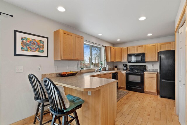 1101 E Gallatin Ave, Belgrade, MT 59714 - kitchen featuring a sink, light brown cabinetry, a peninsula, black appliances, and a breakfast bar area