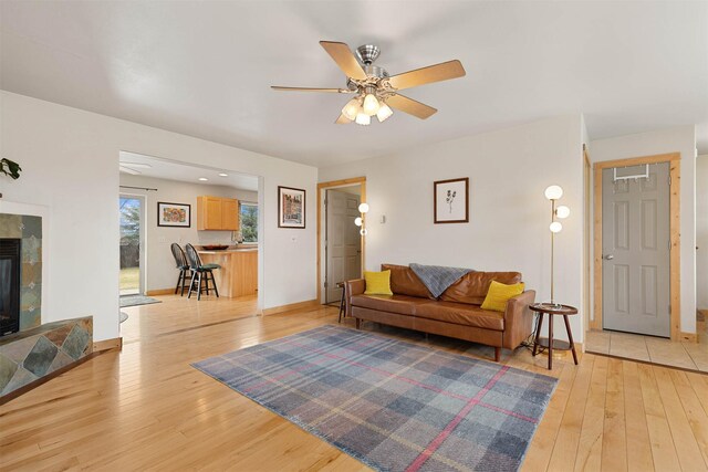 1101 E Gallatin Ave, Belgrade, MT 59714 - living area with light wood-style flooring, a tiled fireplace, ceiling fan, and baseboards