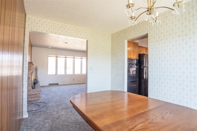 dining room featuring visible vents, carpet, a chandelier, a textured ceiling, and wallpapered walls