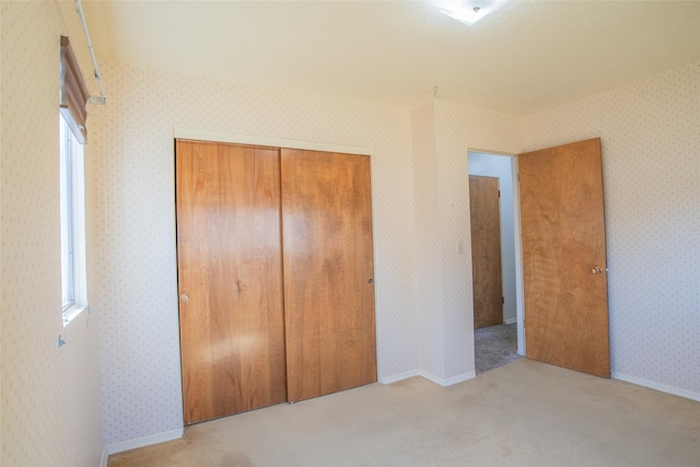 unfurnished bedroom featuring a closet, baseboards, carpet, and wallpapered walls