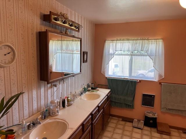708 Johnson Ln, Superior, MT 59872 - bathroom featuring a sink, baseboards, wallpapered walls, and double vanity
