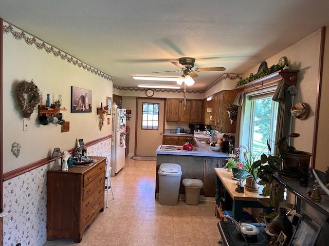 708 Johnson Ln, Superior, MT 59872 - kitchen featuring brown cabinets, freestanding refrigerator, a peninsula, a ceiling fan, and light floors