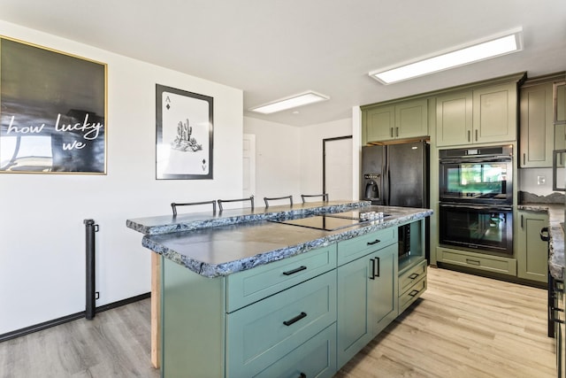 32306 St Ignatius Airport Rd, Saint Ignatius, MT 59865 - kitchen featuring light wood finished floors, black appliances, green cabinetry, and dark stone counters