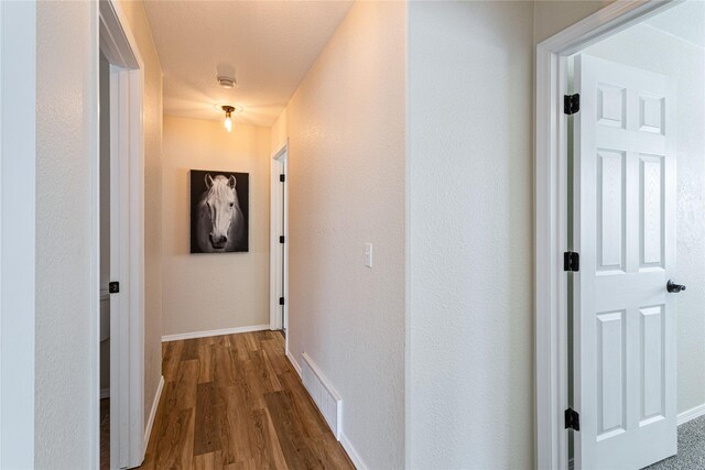 hallway with baseboards, dark wood finished floors, and visible vents