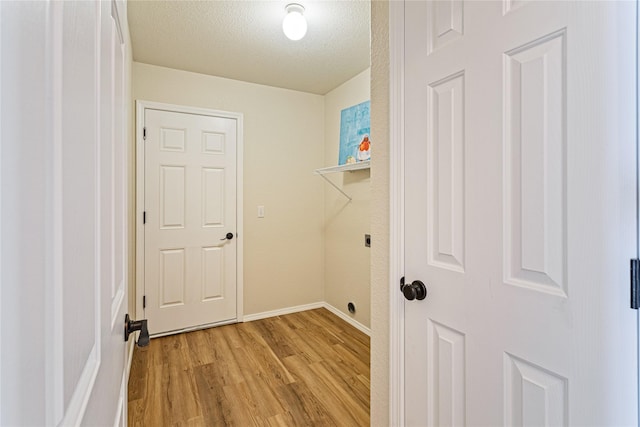laundry room with laundry area, light wood-style floors, a textured ceiling, hookup for an electric dryer, and baseboards