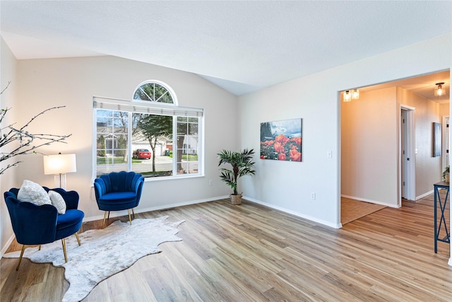 sitting room with baseboards, light wood finished floors, and lofted ceiling