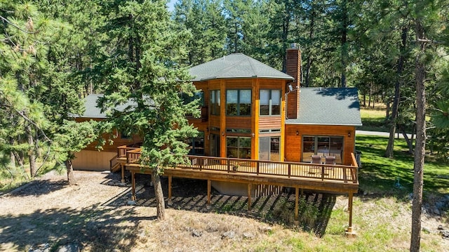 196 Pine Needle Ln, Bigfork, MT 59911 - back of house featuring a wooden deck, a chimney, and a shingled roof