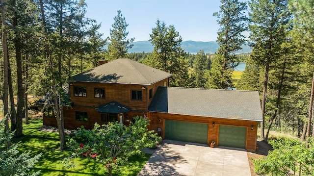 196 Pine Needle Ln, Bigfork, MT 59911 - chalet / cabin featuring a garage, driveway, a chimney, roof with shingles, and a front lawn