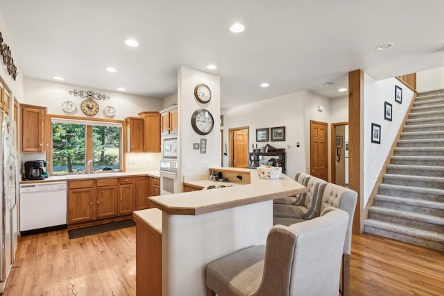196 Pine Needle Ln, Bigfork, MT 59911 - kitchen featuring white appliances, a peninsula, a kitchen bar, recessed lighting, and light wood-style floors