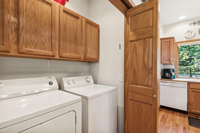 196 Pine Needle Ln, Bigfork, MT 59911 - laundry room with independent washer and dryer, cabinet space, and light wood-style flooring