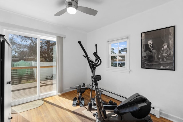 exercise area featuring a baseboard heating unit, wood finished floors, and a wealth of natural light