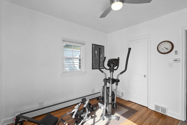 exercise area with baseboard heating, a ceiling fan, wood finished floors, and visible vents