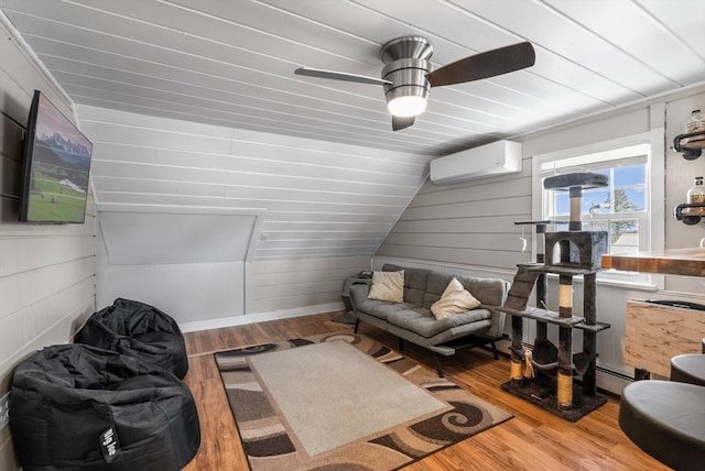 living room with a wall mounted air conditioner, wood walls, wood finished floors, a baseboard radiator, and ceiling fan