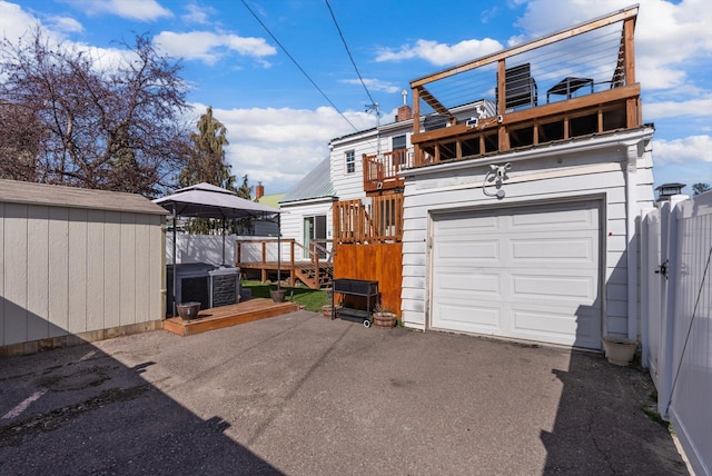 garage with cooling unit, driveway, and fence